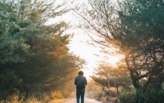 Man walking a quiet path at sunrise, representing a fresh start in sober living